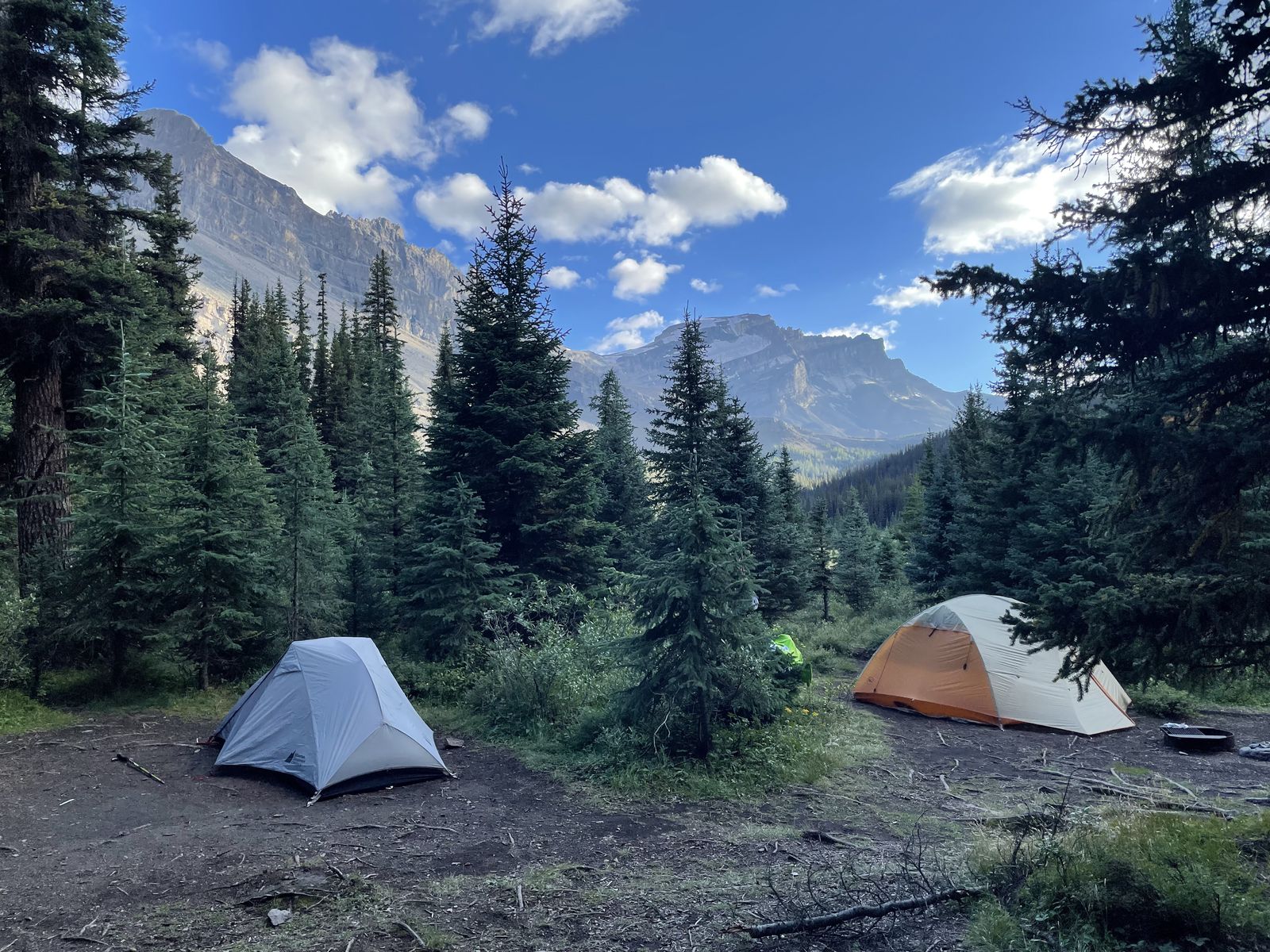 Two tents on side-by-side campsites beneath mountain peaks